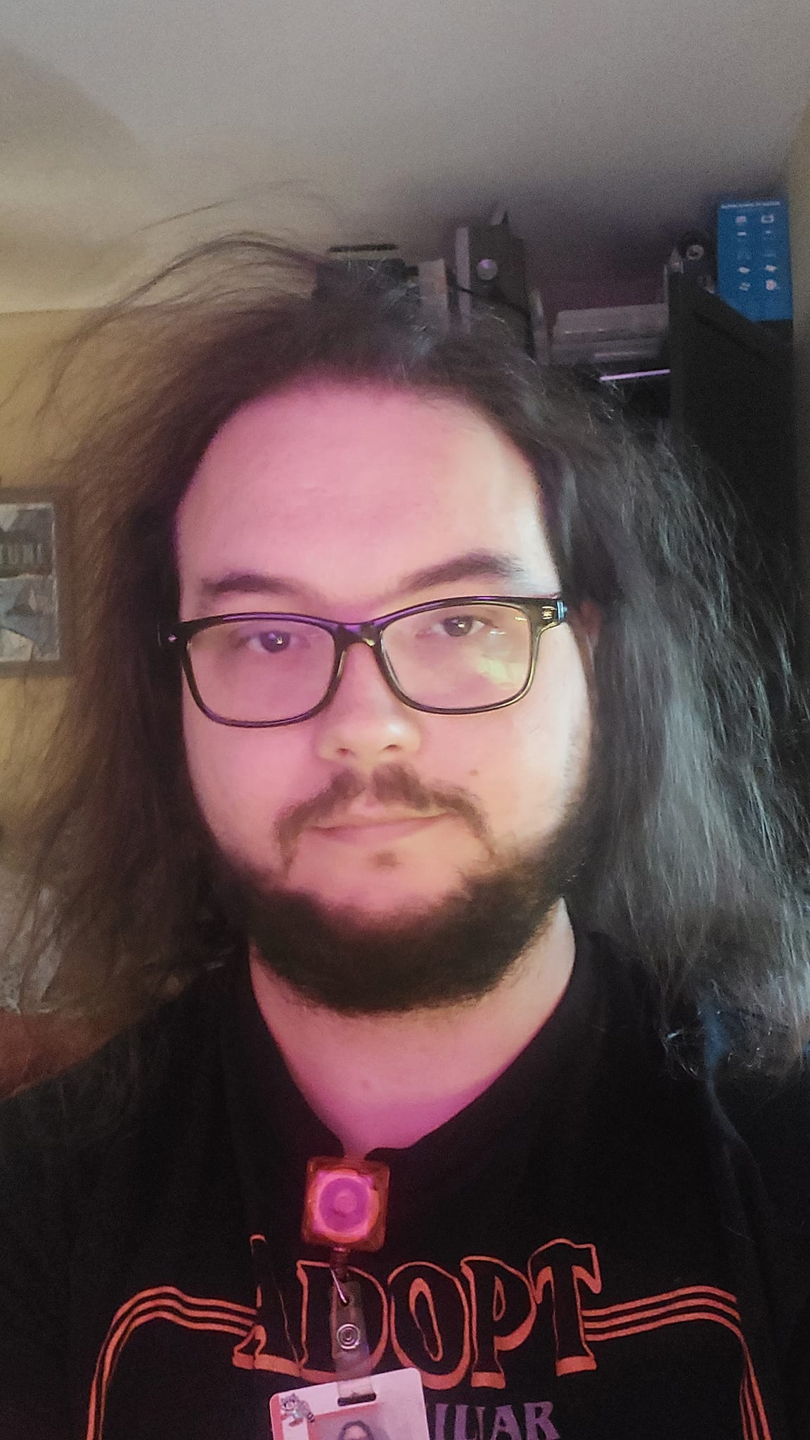 A man with long dark crazy hair sits at a computer chair